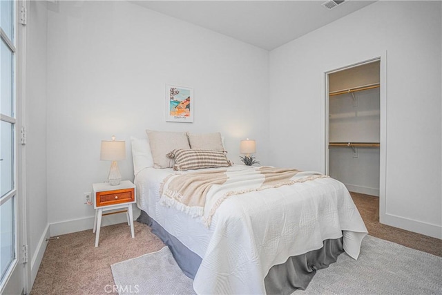 carpeted bedroom with a spacious closet, a closet, visible vents, and baseboards