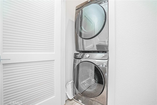 washroom with laundry area, stacked washing maching and dryer, and wood finished floors