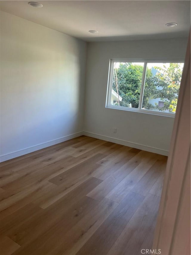 spare room featuring recessed lighting, wood finished floors, and baseboards