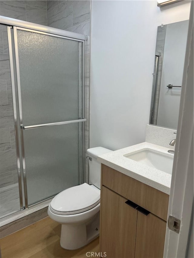 full bathroom with toilet, a stall shower, wood finished floors, and vanity