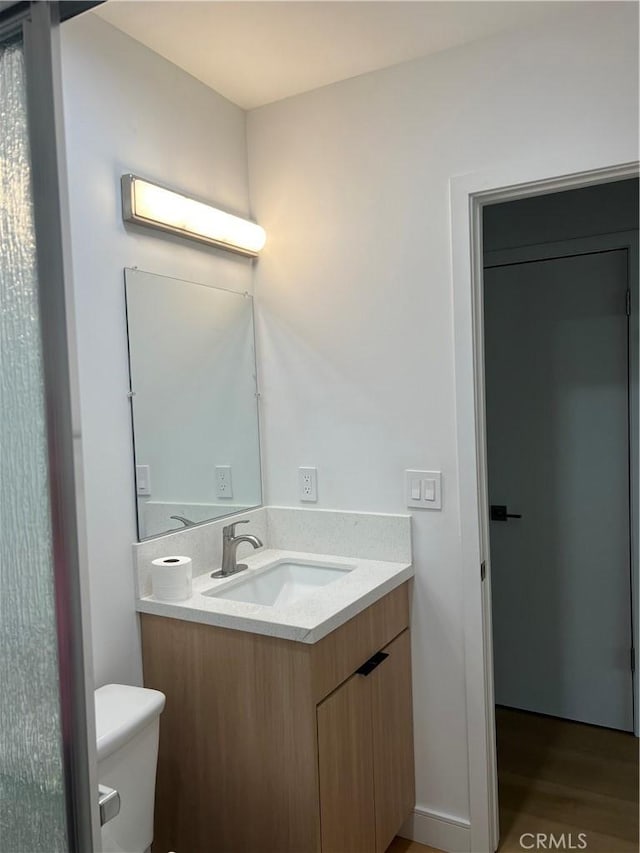 half bath with vanity, toilet, and wood finished floors