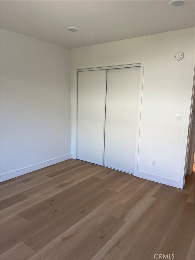 unfurnished bedroom featuring a closet, baseboards, and wood finished floors