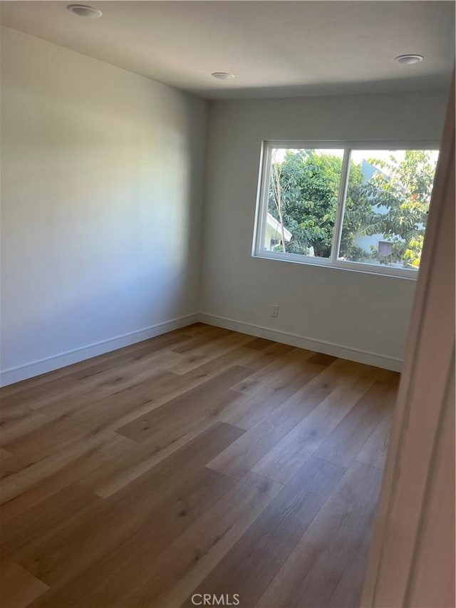 empty room featuring baseboards, wood finished floors, and recessed lighting