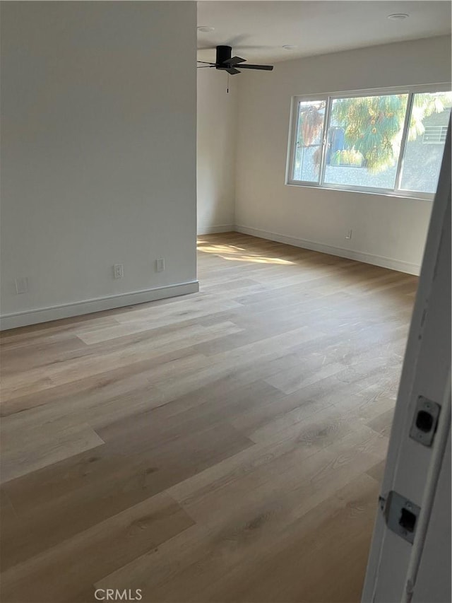 empty room featuring ceiling fan, baseboards, and light wood-style floors