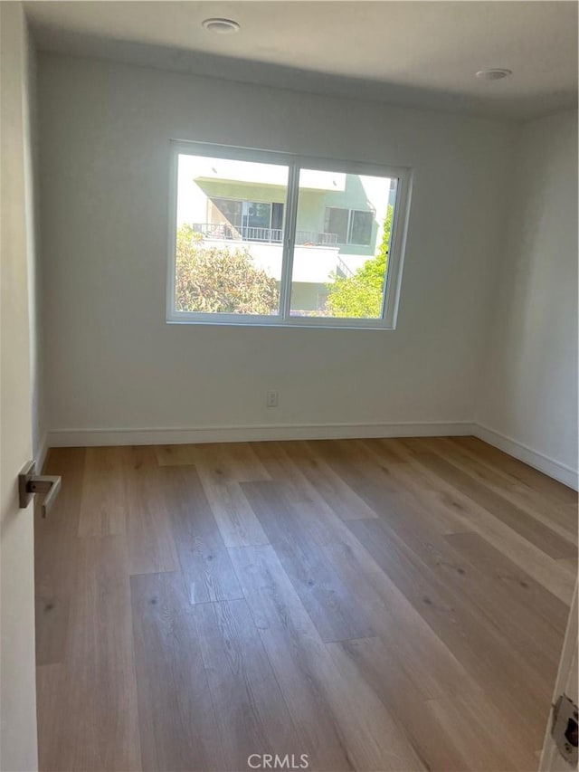 empty room featuring plenty of natural light, baseboards, and wood finished floors