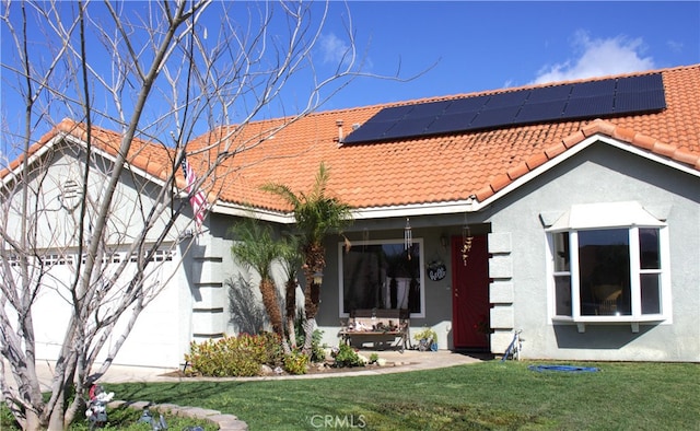 back of house featuring roof mounted solar panels, stucco siding, a tiled roof, and a lawn