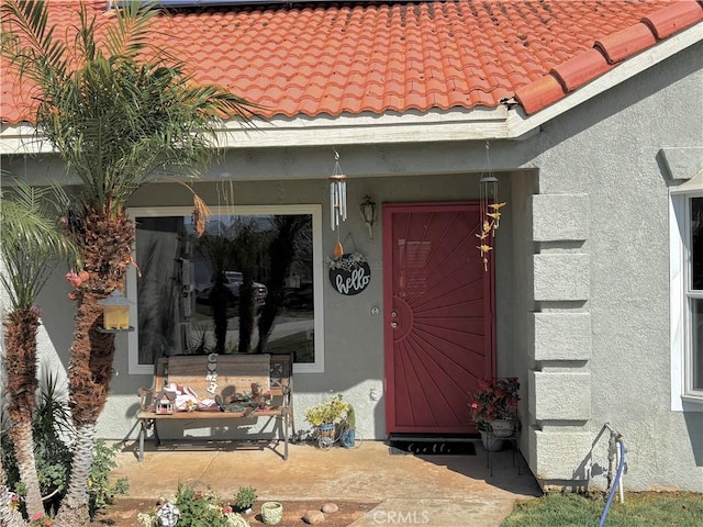 doorway to property with a tile roof and stucco siding