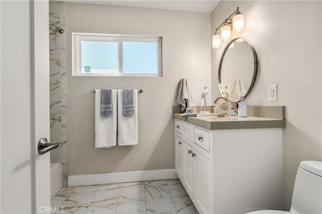 bathroom featuring washtub / shower combination, vanity, toilet, marble finish floor, and baseboards