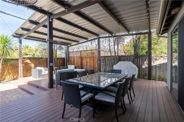 wooden terrace with outdoor dining space, area for grilling, and a fenced backyard