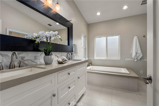 full bathroom with tile patterned flooring, a sink, a garden tub, and visible vents