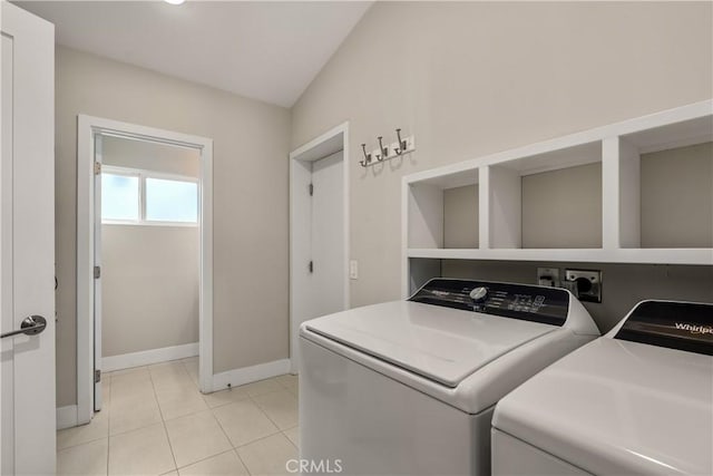 clothes washing area with light tile patterned floors, laundry area, washer and dryer, and baseboards