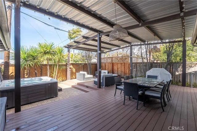 deck with a grill, outdoor dining area, a fenced backyard, and a hot tub