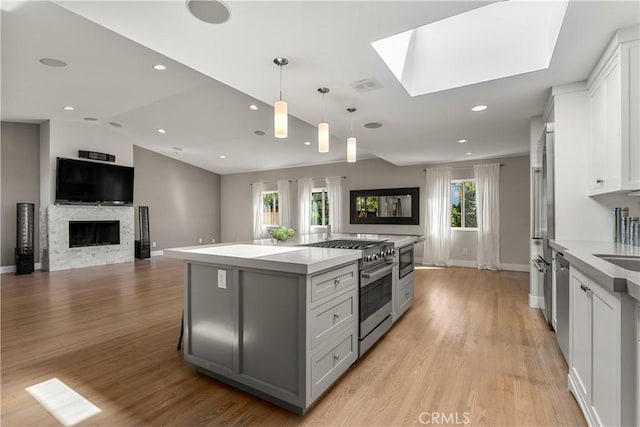 kitchen with a center island, vaulted ceiling with skylight, stainless steel appliances, and light wood-style flooring