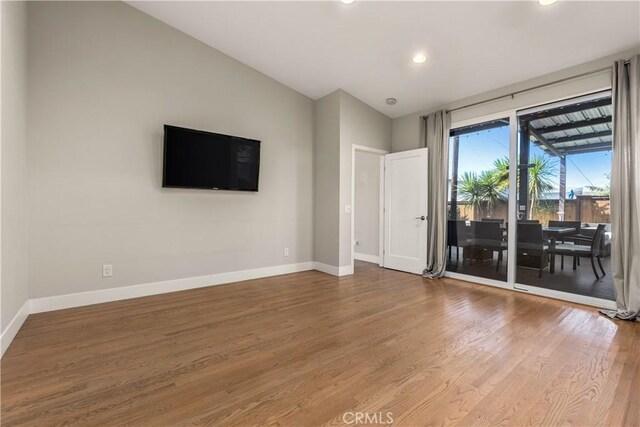 empty room featuring recessed lighting, baseboards, vaulted ceiling, and wood finished floors