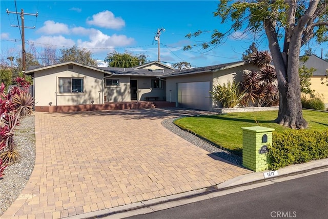 ranch-style home with stucco siding, decorative driveway, a garage, and a front yard