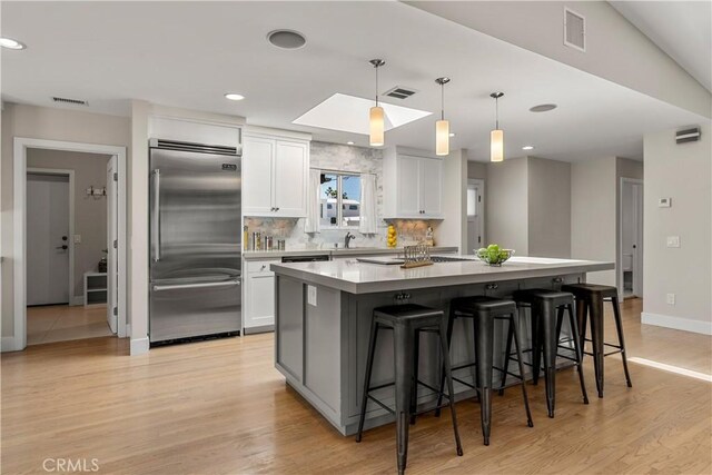 kitchen featuring built in refrigerator, white cabinets, baseboards, and visible vents