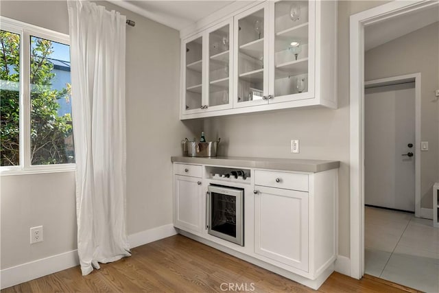 bar featuring baseboards, light wood-style floors, and a dry bar