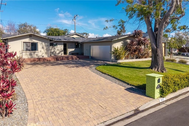single story home with decorative driveway, a garage, a front yard, and stucco siding