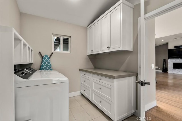 washroom with washer and dryer, baseboards, cabinet space, and light tile patterned floors