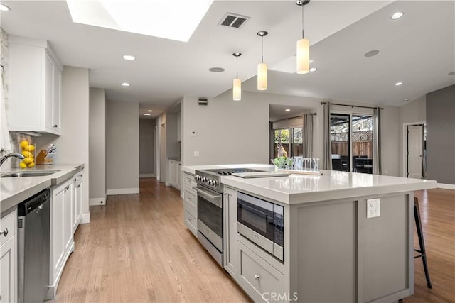 kitchen with visible vents, light wood finished floors, a sink, white cabinets, and appliances with stainless steel finishes