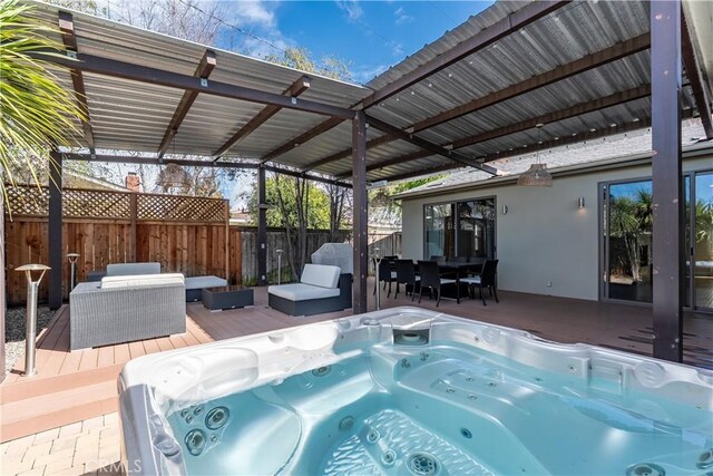 exterior space with a hot tub, fence, and outdoor dining space