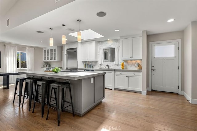 kitchen with visible vents, stainless steel built in fridge, a spacious island, a sink, and white cabinets
