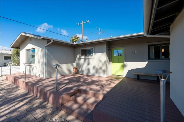 back of property with a wooden deck and stucco siding