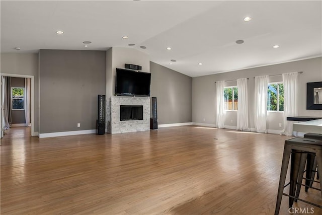 unfurnished living room featuring wood finished floors, a fireplace, baseboards, recessed lighting, and vaulted ceiling