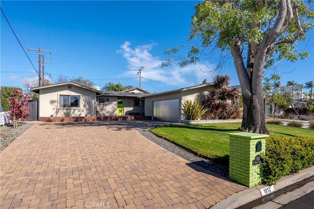 ranch-style house featuring a garage, decorative driveway, a front lawn, and stucco siding