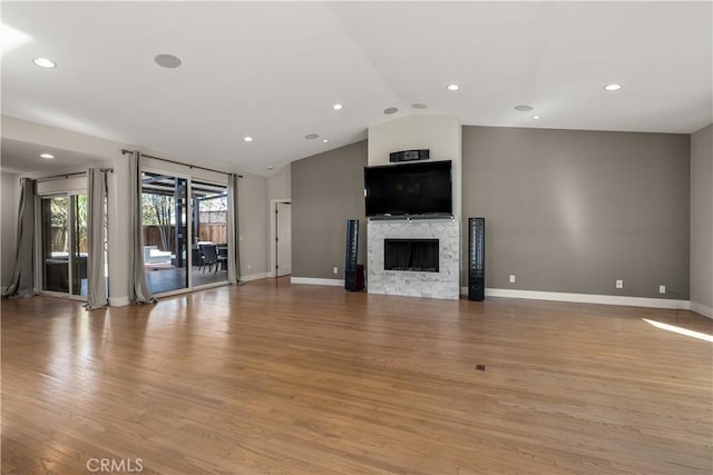 unfurnished living room with lofted ceiling, baseboards, light wood finished floors, and a premium fireplace