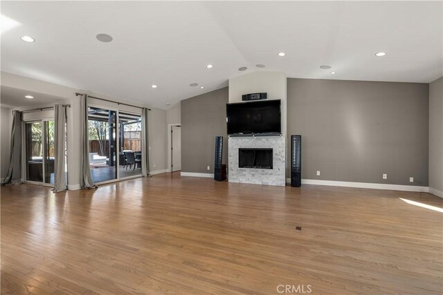 unfurnished living room with a fireplace, vaulted ceiling, baseboards, recessed lighting, and light wood-style flooring