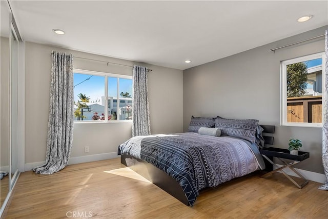 bedroom with baseboards, multiple windows, and wood finished floors