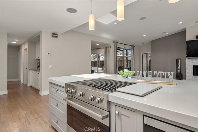 kitchen with light countertops, recessed lighting, light wood finished floors, and high end range