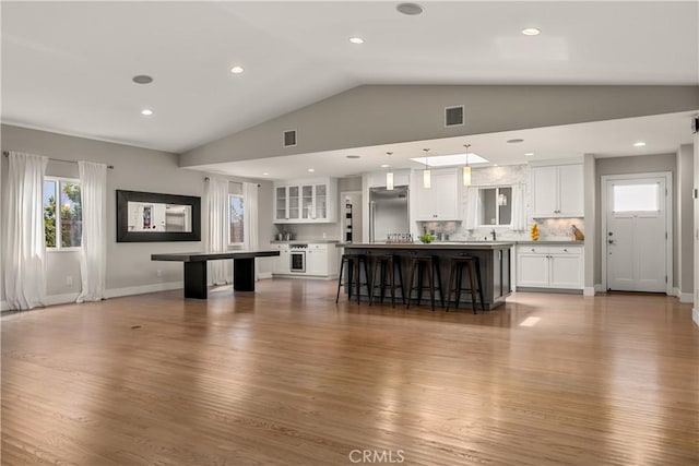 unfurnished living room featuring lofted ceiling, wood finished floors, and visible vents