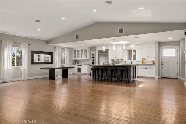 unfurnished living room with lofted ceiling, recessed lighting, wood finished floors, and visible vents