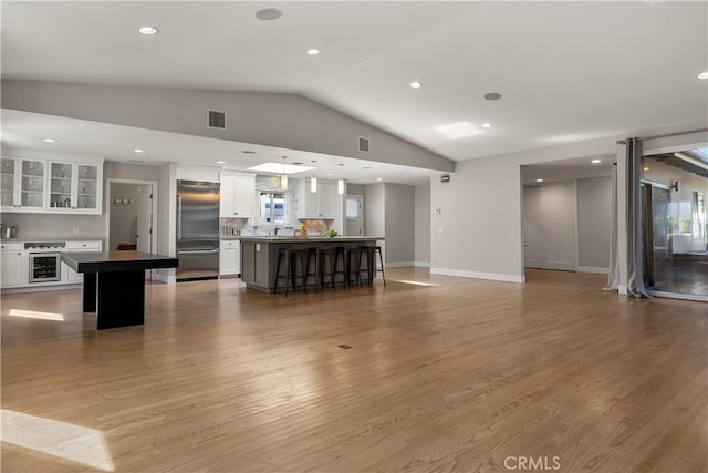 unfurnished living room with visible vents, recessed lighting, baseboards, light wood-style floors, and lofted ceiling