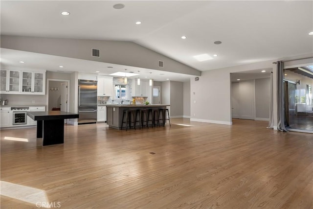 unfurnished living room featuring visible vents, recessed lighting, light wood-style floors, and vaulted ceiling
