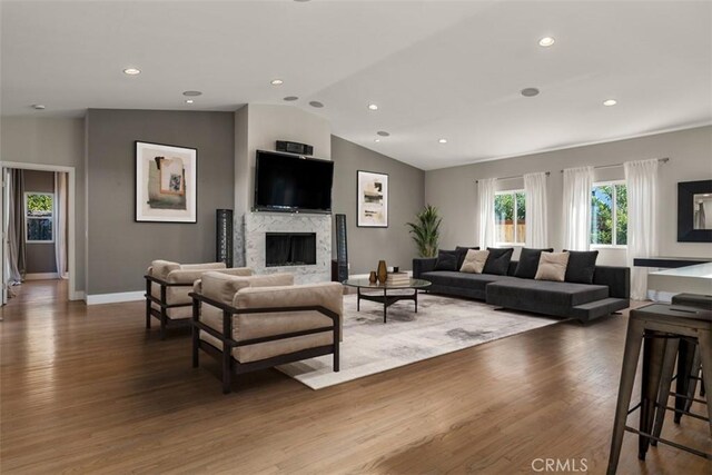 living room featuring baseboards, wood finished floors, vaulted ceiling, and a fireplace