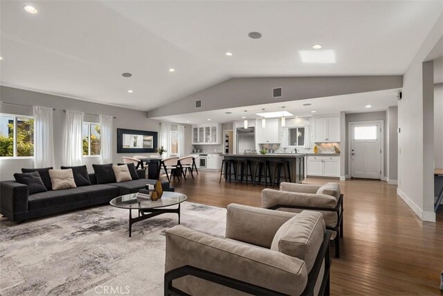 living room with a healthy amount of sunlight, visible vents, light wood finished floors, and lofted ceiling