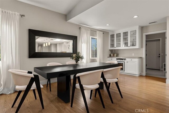 dining space featuring recessed lighting, a bar, light wood finished floors, and visible vents