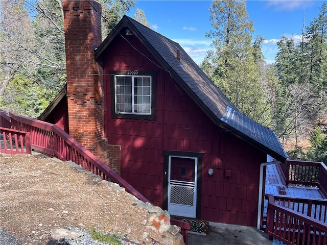 view of front of home featuring a chimney and roof with shingles