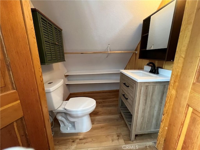 half bathroom with wood finished floors, vanity, and toilet