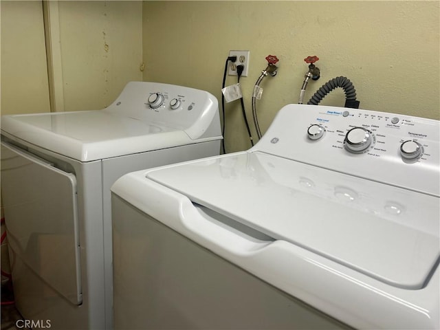 laundry room with laundry area, a textured wall, and washing machine and clothes dryer