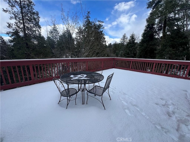 wooden terrace featuring outdoor dining area and a view of trees