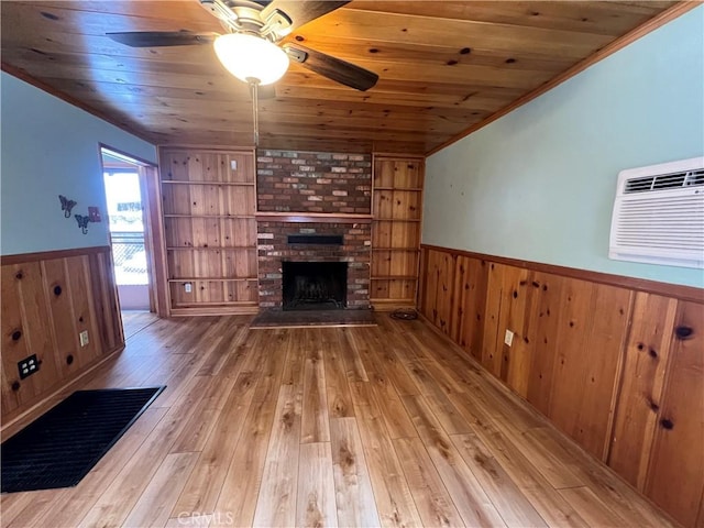 unfurnished living room featuring built in features, a wainscoted wall, wood ceiling, wood-type flooring, and a fireplace