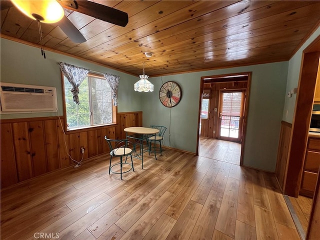 dining space featuring wainscoting, a wall mounted AC, wooden ceiling, and light wood-style flooring