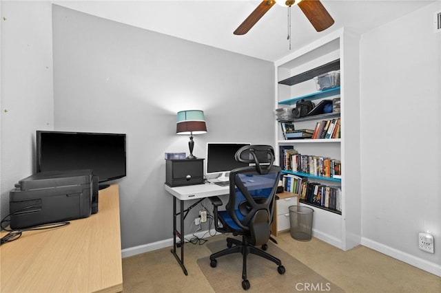 office space with visible vents, built in shelves, baseboards, carpet, and a ceiling fan