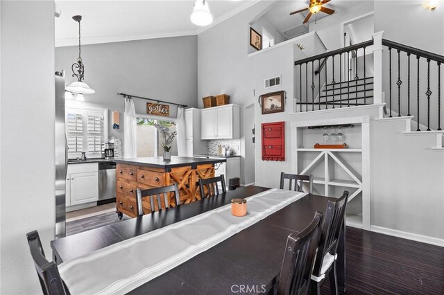 dining space featuring visible vents, dark wood finished floors, stairway, ornamental molding, and a high ceiling