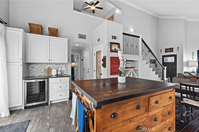 kitchen with visible vents, wine cooler, arched walkways, and crown molding