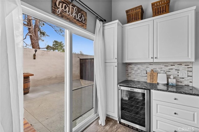 interior space featuring wine cooler, backsplash, and white cabinetry